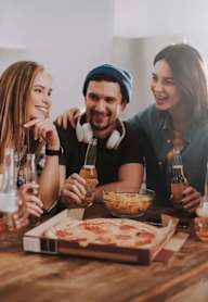 Three people enjoying a meal and drinks together.
