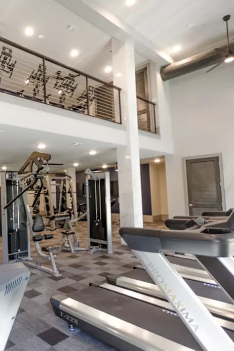 A gym with a variety of equipment including treadmills, weights, and exercise machines.