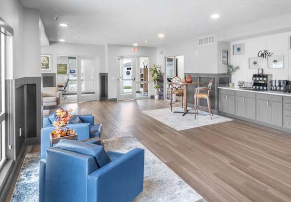 A spacious living room with a blue sofa and a kitchen area in the background.