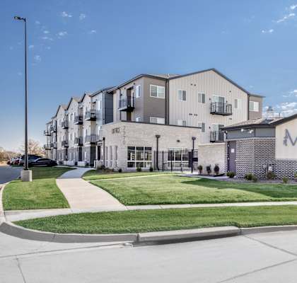The Meadows apartment complex is a modern building with a spacious front lawn.