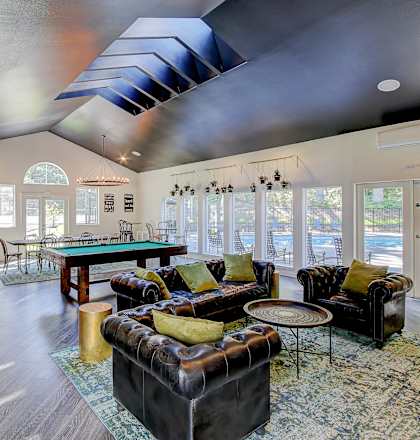 A living room with a black couch and a blue rug.