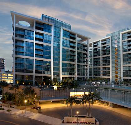 A modern building with glass windows and a bridge connecting two towers.