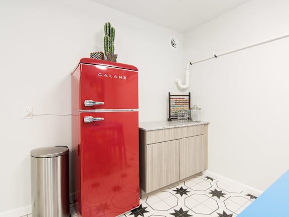 A red Galanz refrigerator with a cactus on top sits in a kitchen.