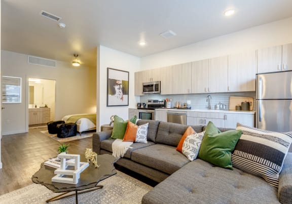 a living room with a couch and a kitchen with a refrigerator