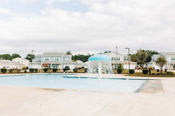 A large swimming pool with lounge chairs and a building in the background.