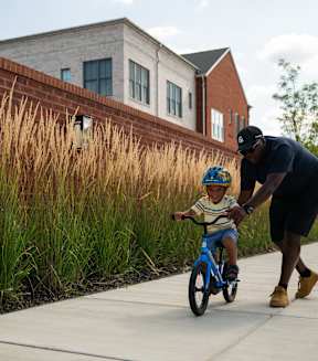 A man is teaching a young boy how to ride a bike.