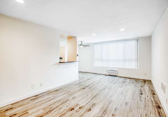 an empty living room with wood flooring and a window