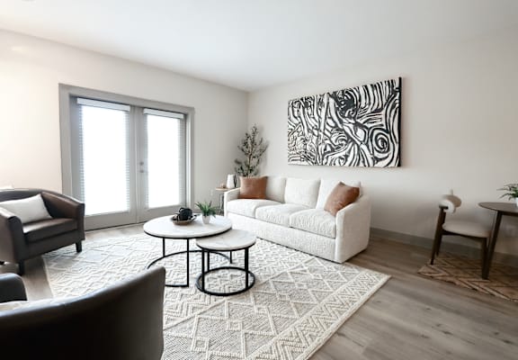 A living room with a white couch, a coffee table, and a large abstract painting on the wall.