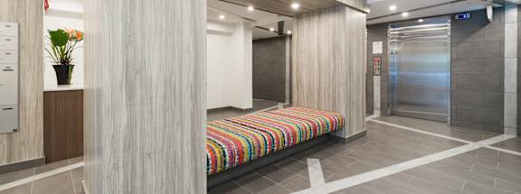 a bench in the lobby of a building with an elevator in the background