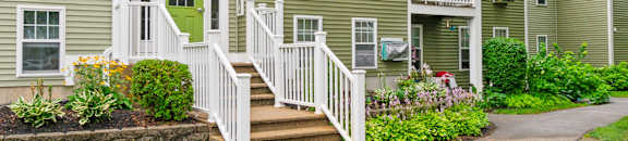 the front of a green house with stairs and a sidewalk at Station Pointe, Mansfield, 02048