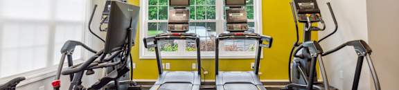 two treadmills and weights in a gym with a window at Station Pointe, Mansfield, 02048