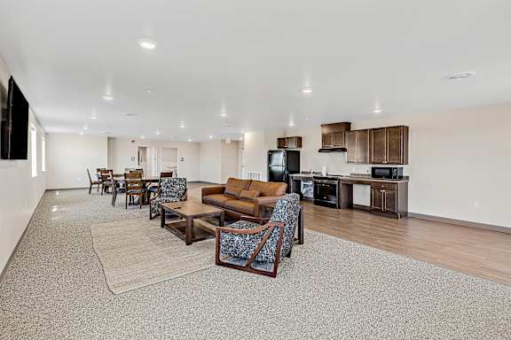 A spacious living room with a grey carpet and wooden furniture.