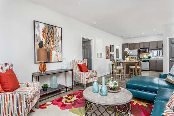 a living room with blue couches and chairs and a dining room with a kitchen