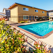 A swimming pool surrounded by a black fence and a white awning.