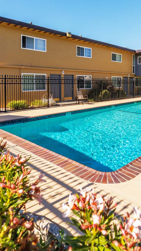 A swimming pool surrounded by a black fence and a white awning.