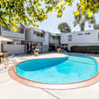 A swimming pool in a backyard with a white fence and a house in the background.