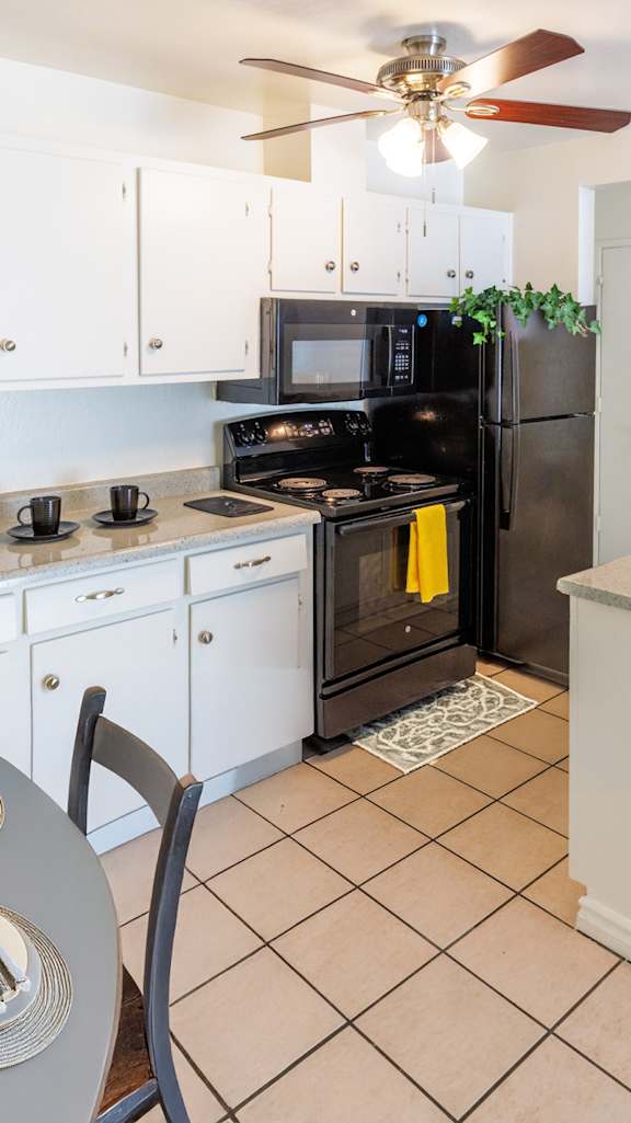 A kitchen with black appliances and white cabinets.
