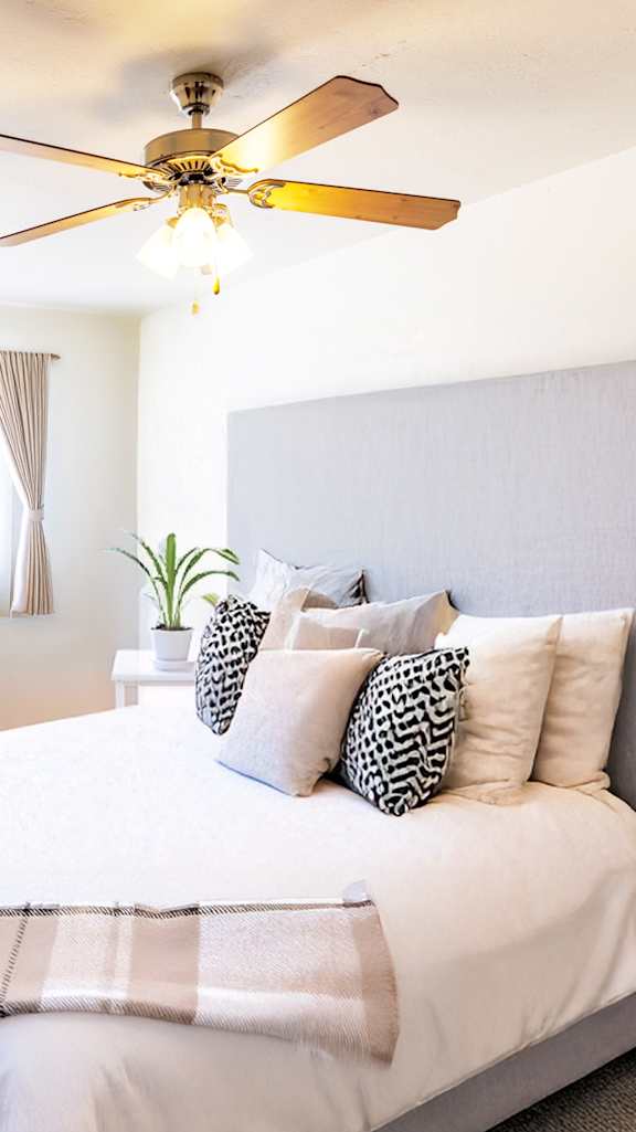 A bedroom with a large bed and a ceiling fan.
