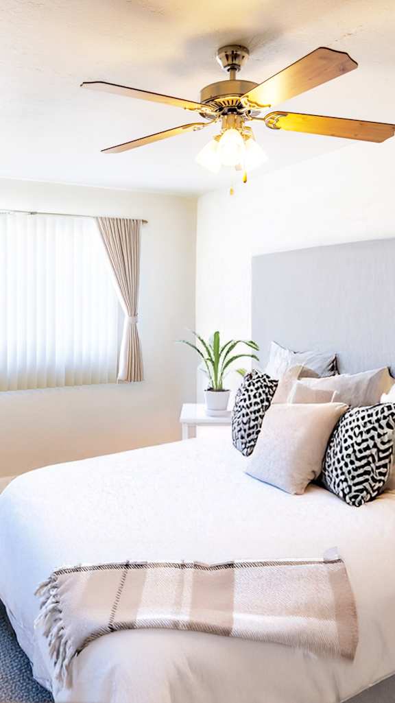 A bedroom with a large bed and a ceiling fan.