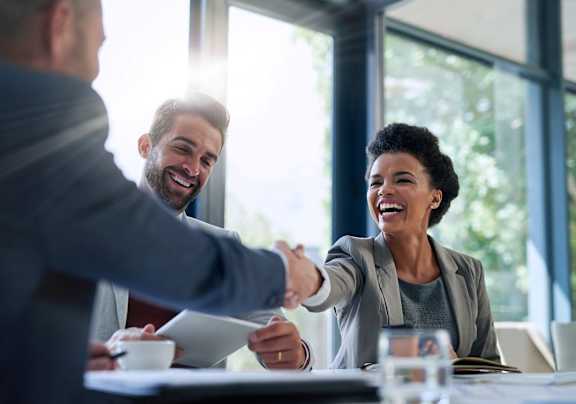 Two people shaking hands in a meeting room.