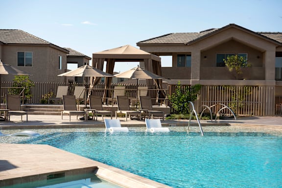 A pool area with a few chairs and umbrellas.