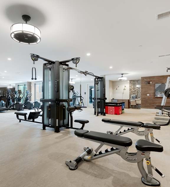 A gym with a variety of equipment including treadmills, weights, and exercise machines.