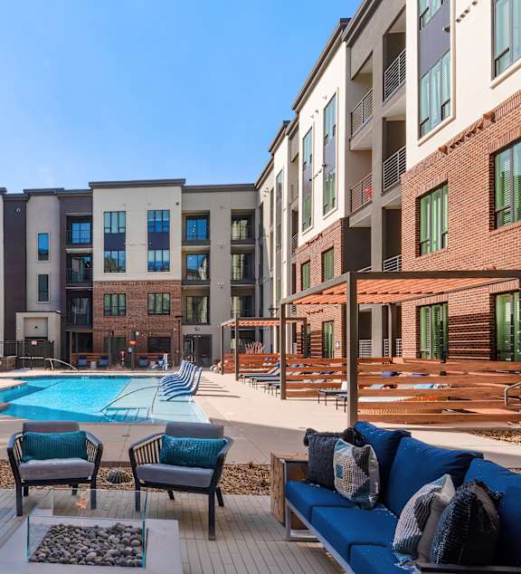A pool area with a blue sofa and chairs.