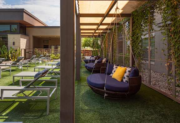 A patio with a swing and a table.