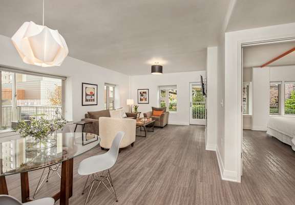 A modern living room with a glass dining table and white chairs.