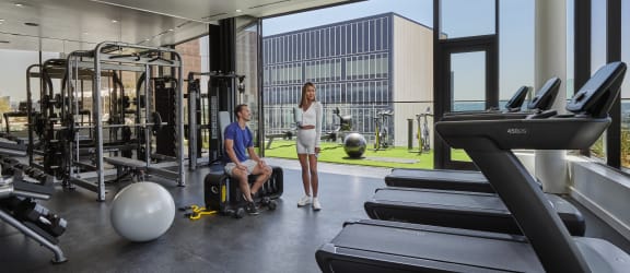 a man in a wheelchair and a woman in a white dress stand in a gym with tread