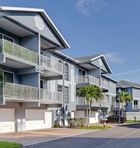 A row of modern apartment buildings with balconies and palm trees.