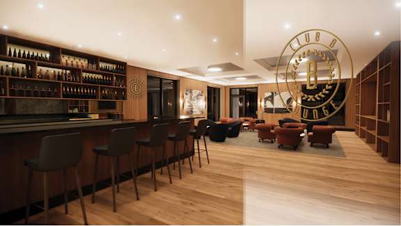 A bar with a clock on the wall and chairs around a table.