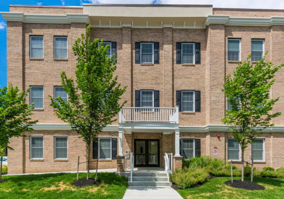 a brick building with a balcony and trees in front of it at Greenway Village Apartments, Metuchen, New Jersey