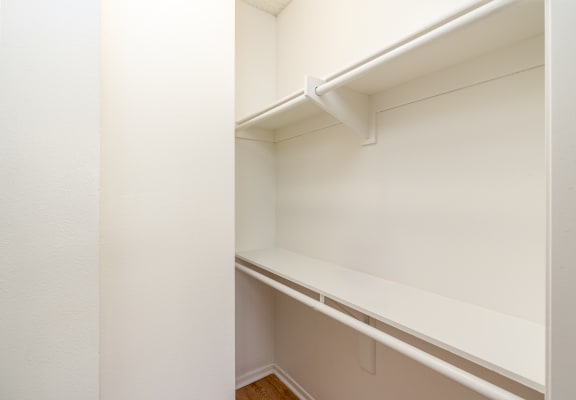 an empty closet with white walls and a white shelf
