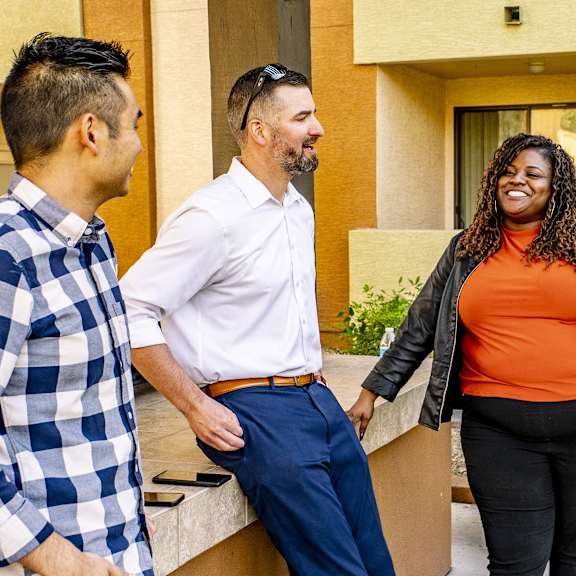 A group of people standing outside of a building at Arctic Sun Apartment Homes.
