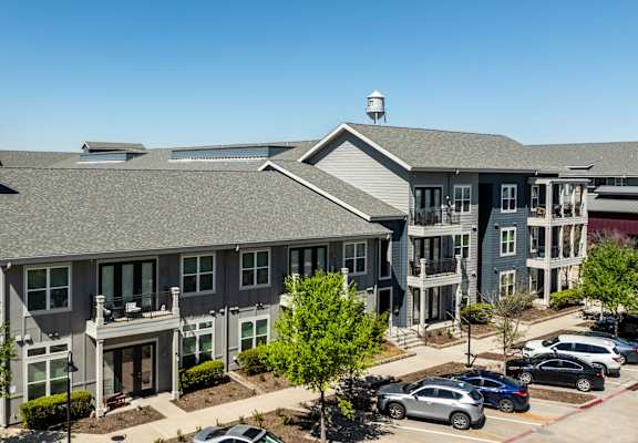 an aerial view of an apartment complex with cars parked in a parking lot