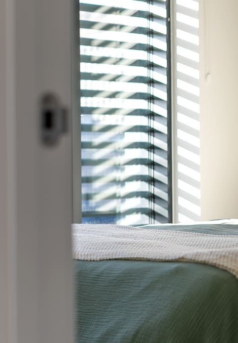 a bedroom with a large window and a bed with a blanket