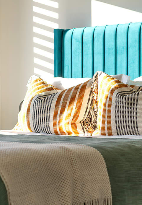 a bed with a blue headboard and pillows on it