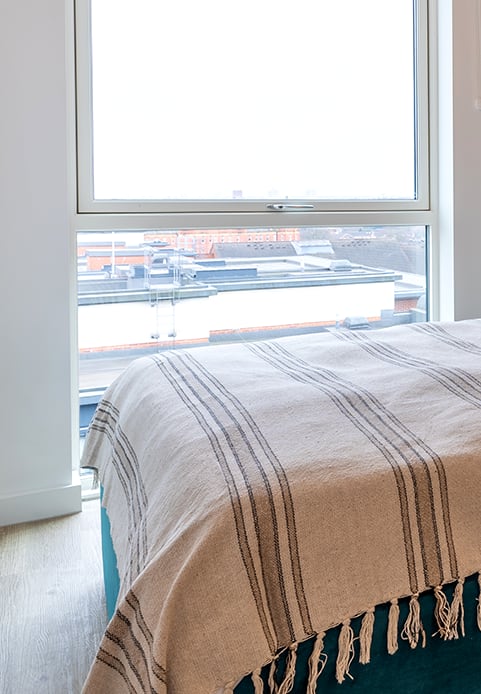 a bedroom with a large window and a bed with a blanket