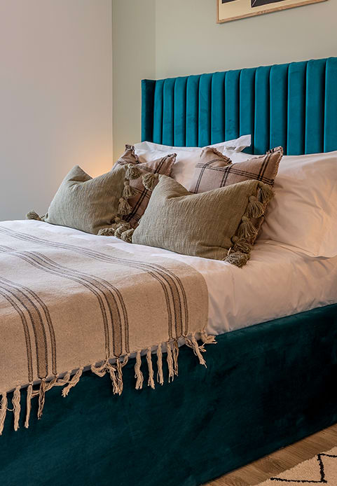 a bed with a blue headboard and pillows on it