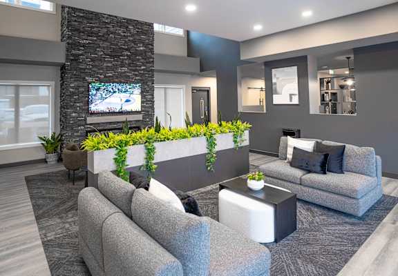 A modern living room with grey couches and a stone pillar.
