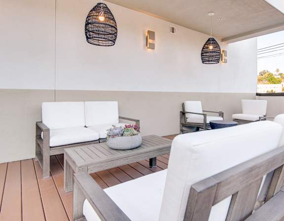 A white couch is on a wooden deck with a table and chairs.