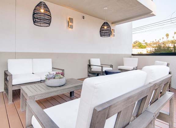 A white couch is on a wooden deck with a table and chairs.