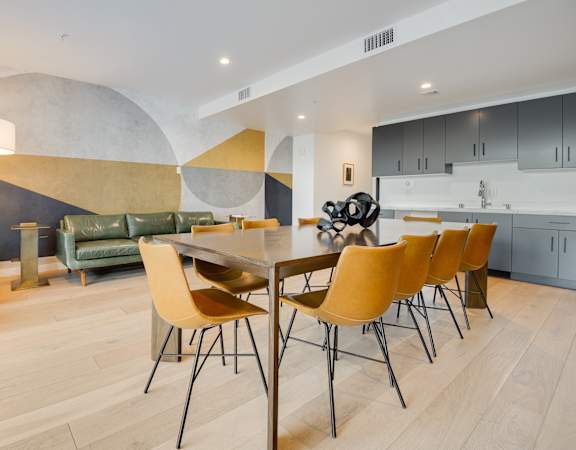 A modern dining room with a wooden table and yellow chairs.