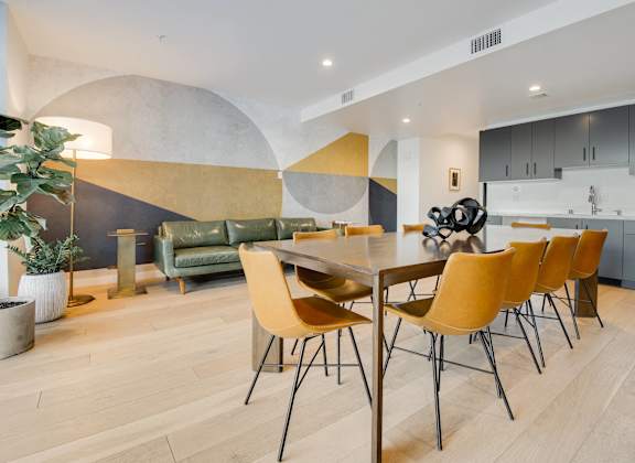 A modern dining room with a wooden table and yellow chairs.