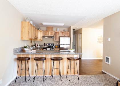 A kitchen with a bar stool in front of it.