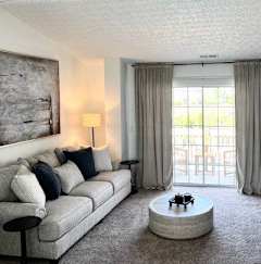 A living room with a grey couch, a coffee table, a television, and a painting on the wall.