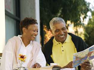 Two people reading a book together outdoors.