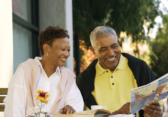 a man and woman sitting at a table reading a map