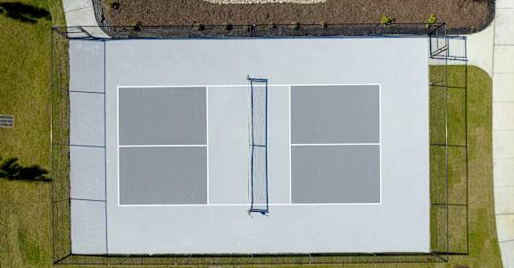 A tennis court with a net and a blue pole at Evolve St. James Apartment Homes Apartments, Southport, NC, 28461